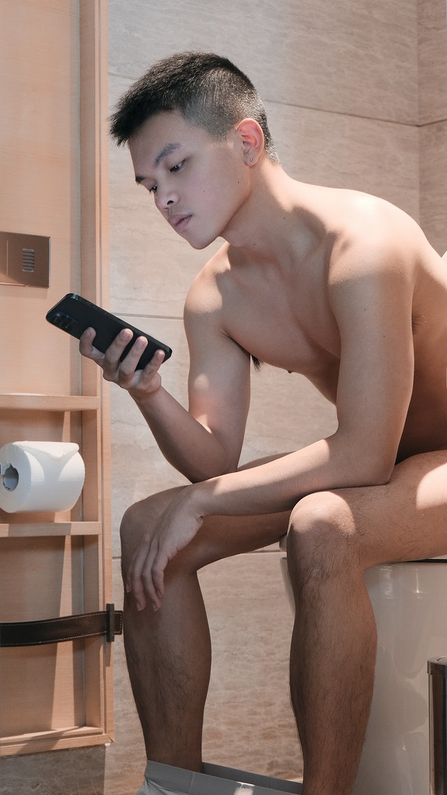 Man on toilet searching herpes symptoms in men